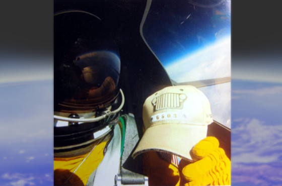 Image of g503 hat in cockpit of U2 with pilot in space suit with the curvature of the earth visible in the background.